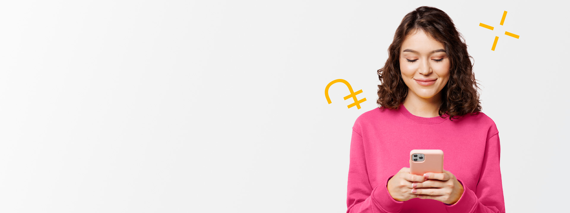 Woman in a pink sweater smiles while looking at her smartphone with currency symbols in the background.