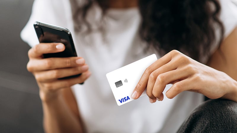 A person holding a phone and a credit card