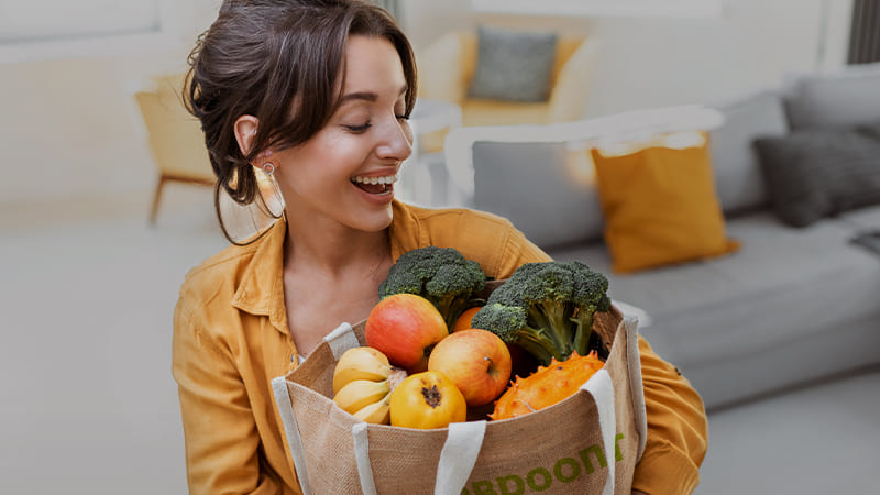 Счастливая женщина с полной сумкой овощей и фруктов