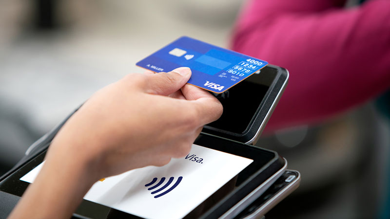 Close up of person using Tap to Pay at a terminal in a store.